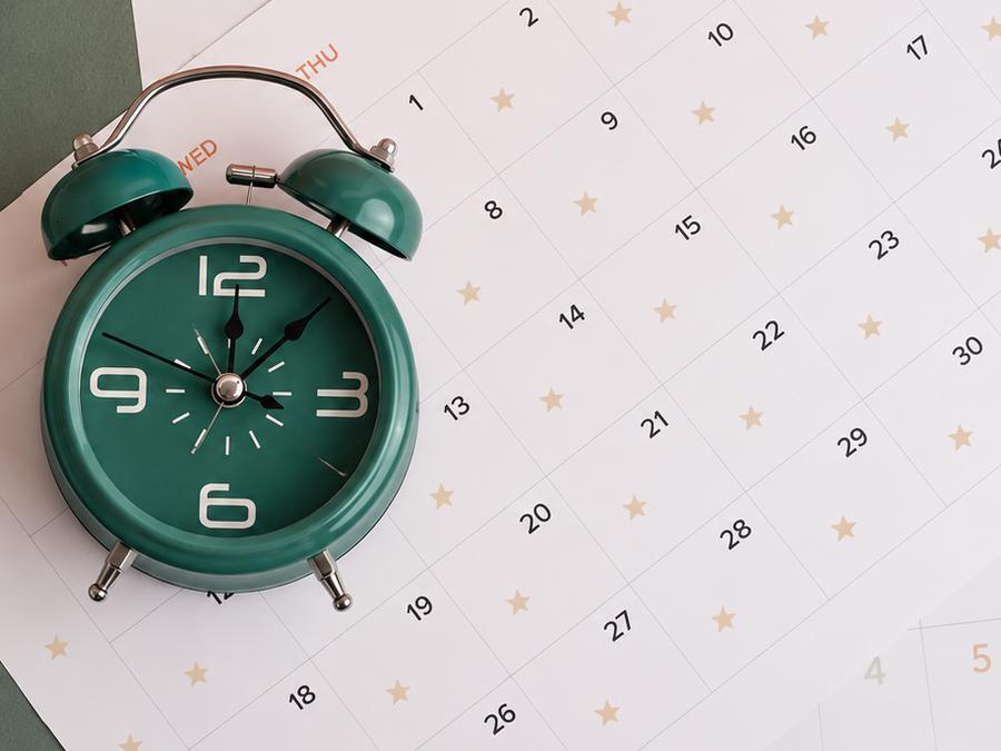 Un despertador verde sobre un calendario