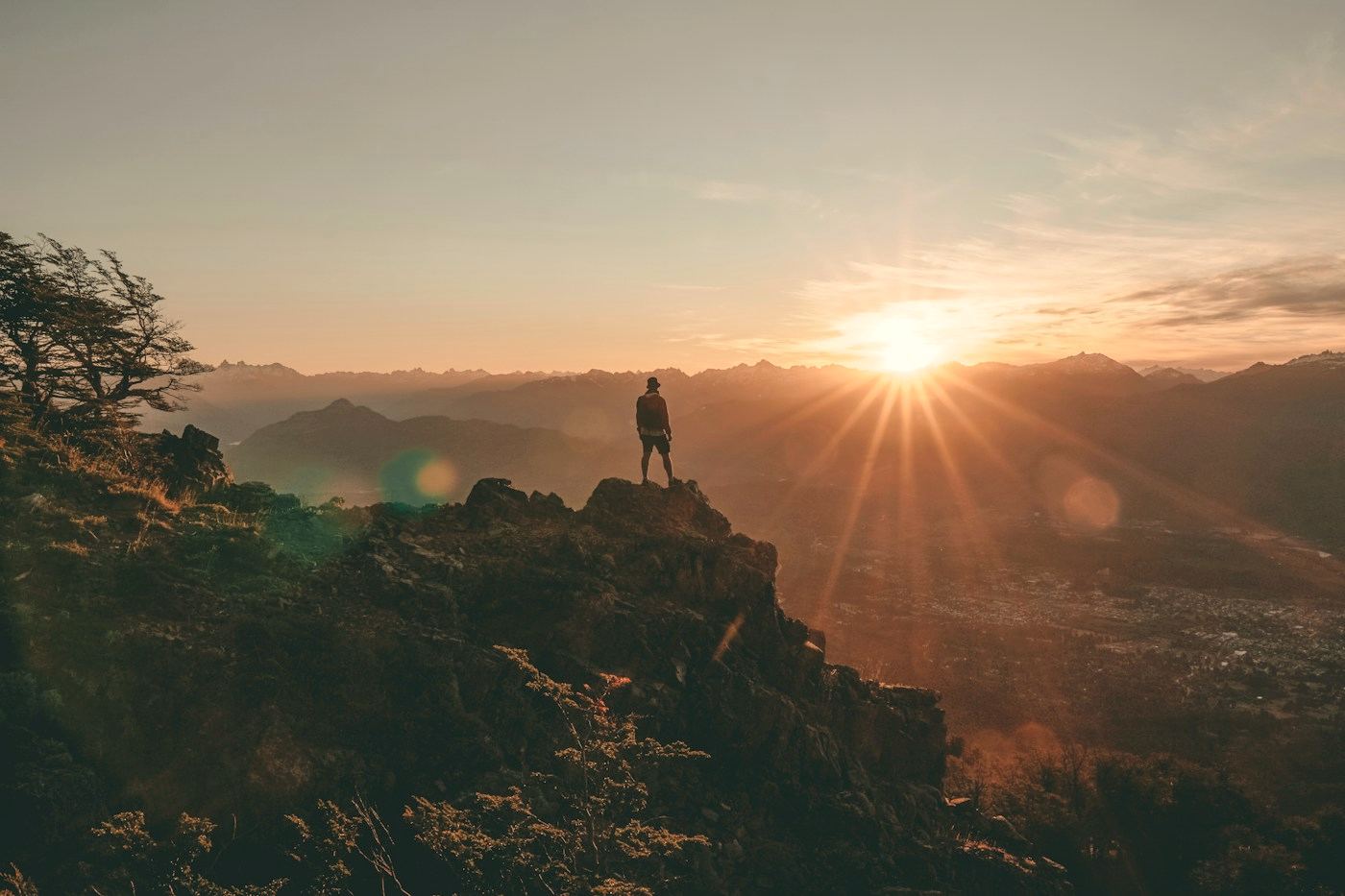 Una persona en lo alto de una montaña mira cómo sale el sol sobre el valle.