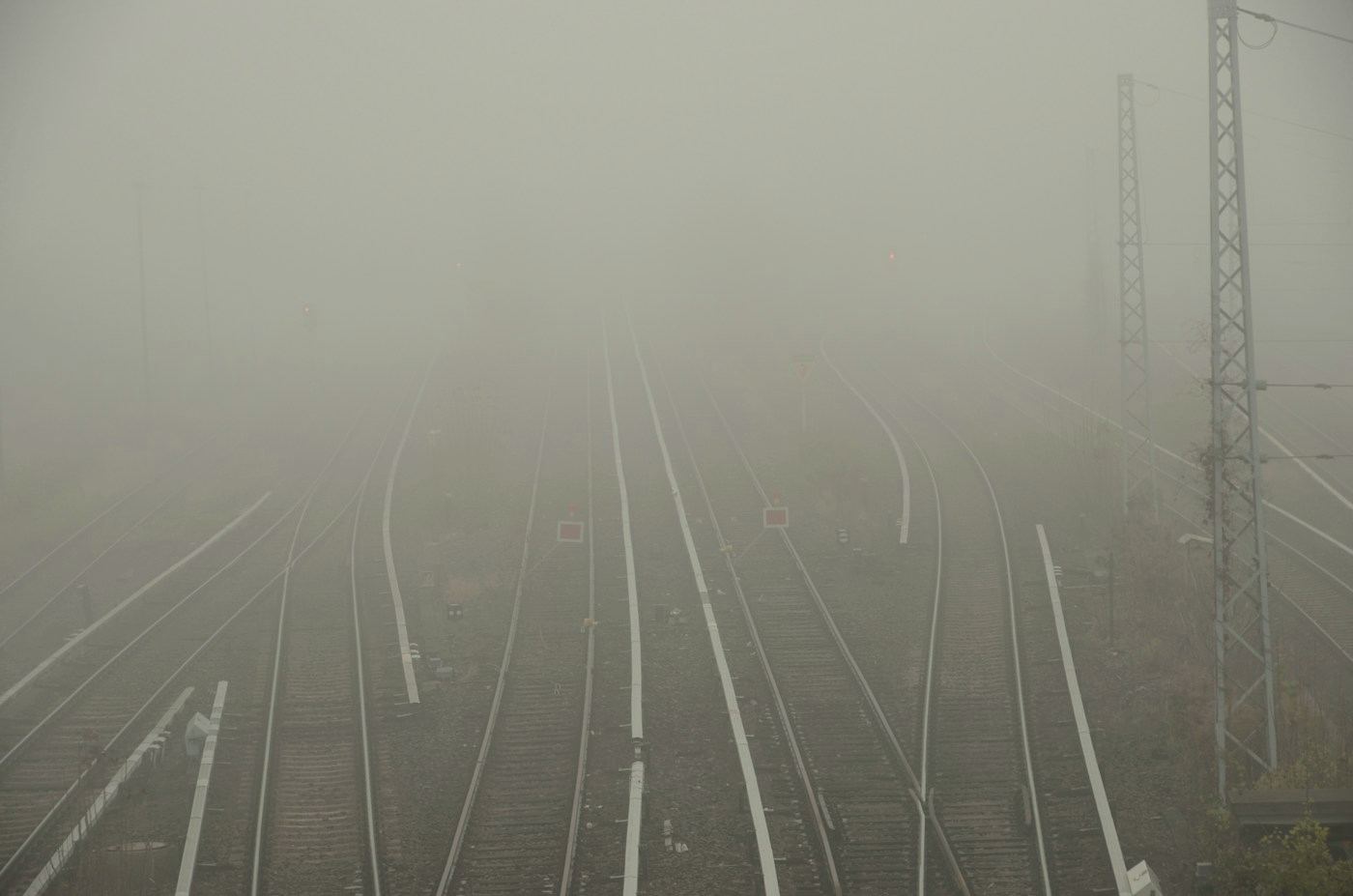 Vías de tren que se separan y se pierden en la niebla.